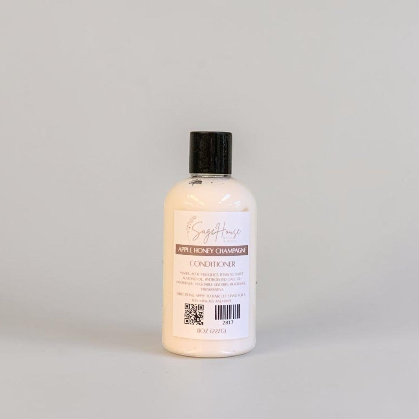 A bottle of conditioner with a black lid and white label on a white background.
