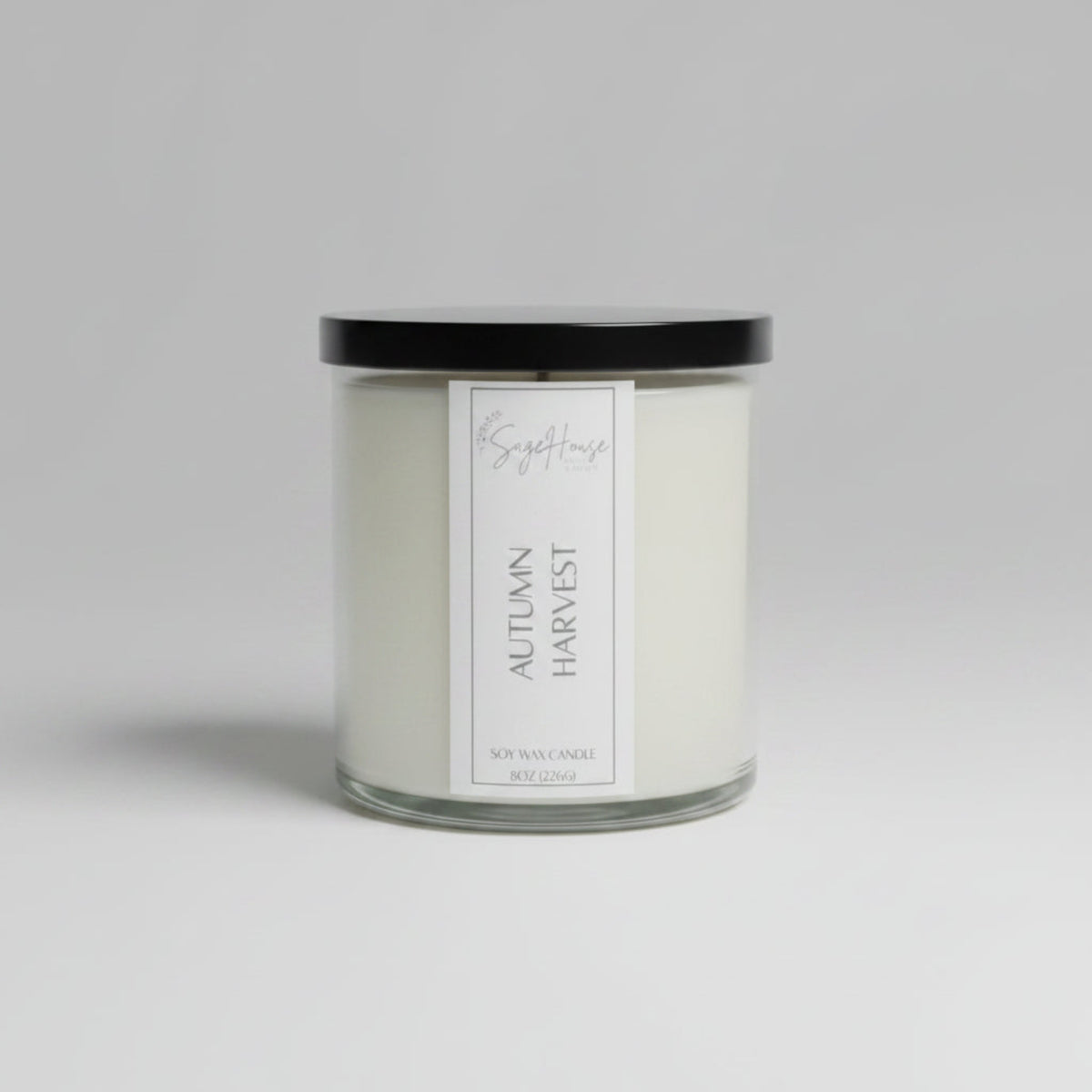 A white soy wax candle in a clear container, placed on a wooden surface, with a label on the front.