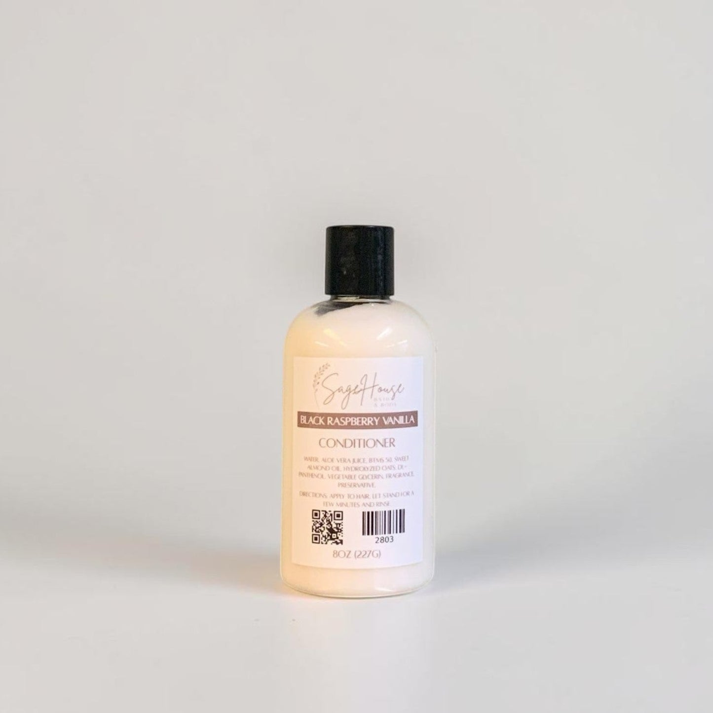 A bottle of conditioner with a black cap and white label. On a white background.