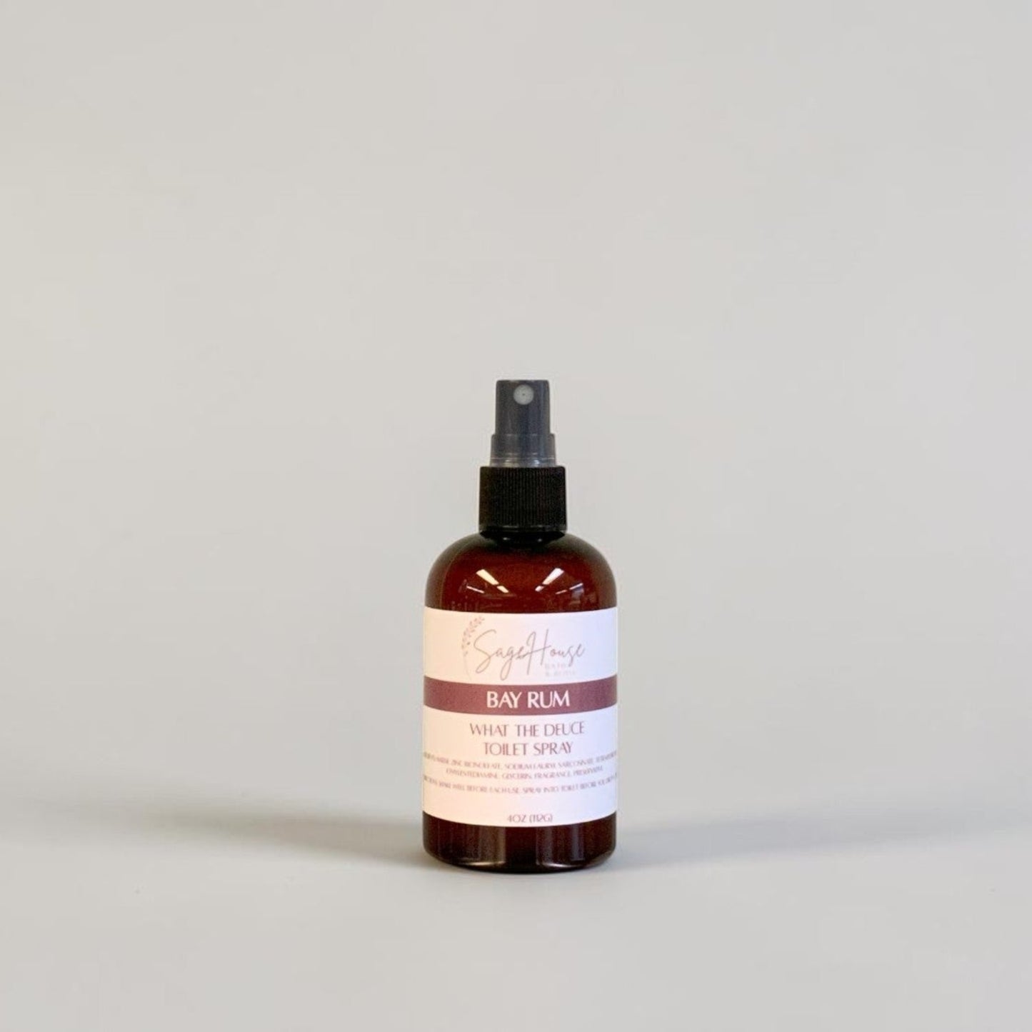 An amber spray bottle with black spray nozzle and white label, standing on a light gray surface against a light gray background.