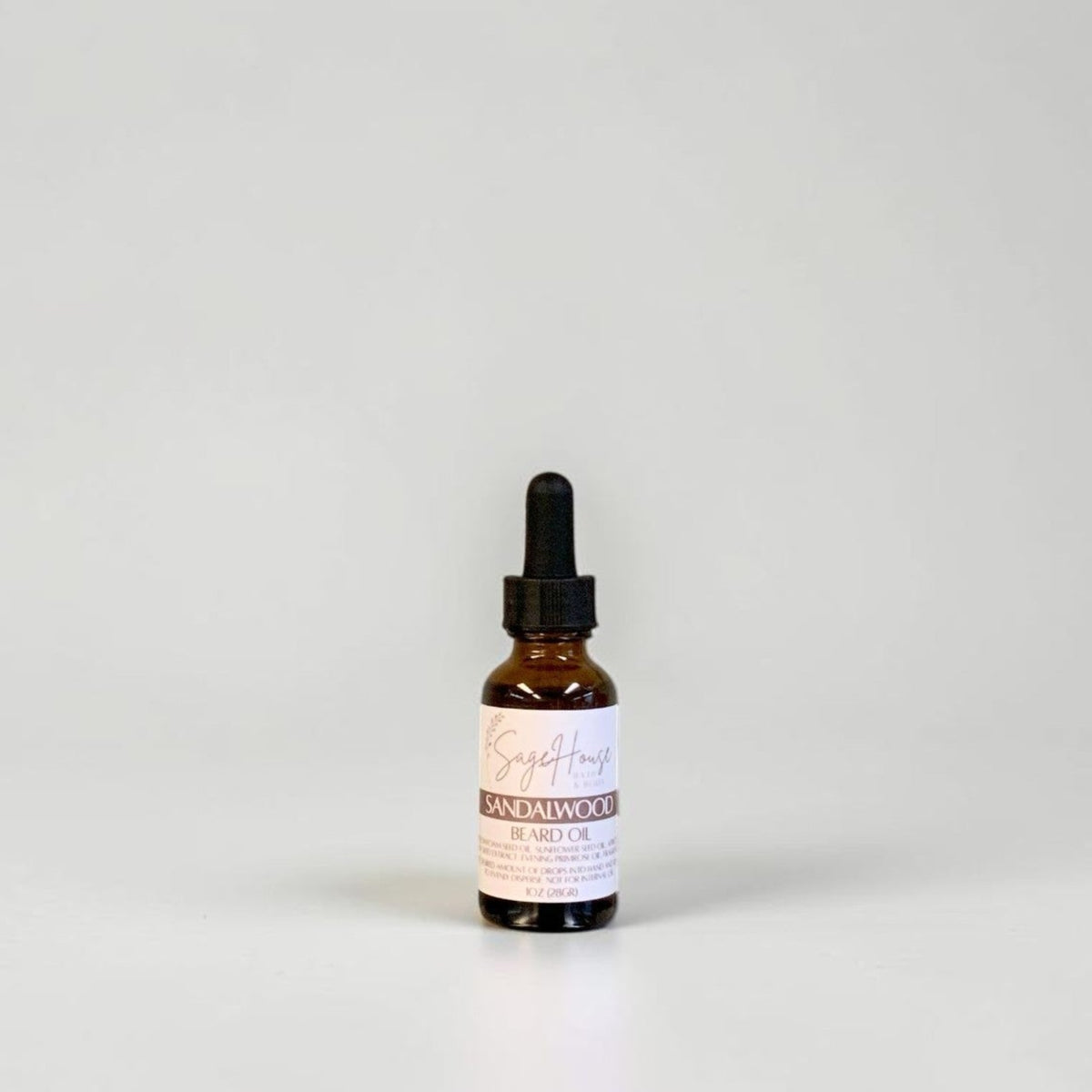 A small amber glass dropper bottle with a black dropper cap and a white label, centered against a plain light gray background.