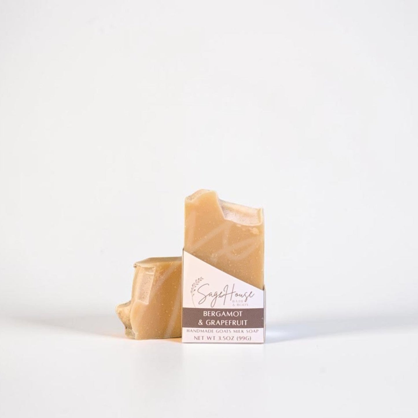 A labeled bar of soap sitting in front of a matching bar of soap. On a white background.