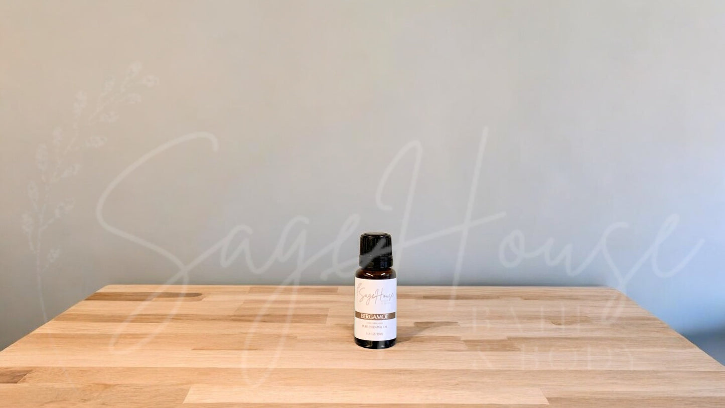A small bottle of bergamot essential oil is placed on a wooden surface with a plain background.