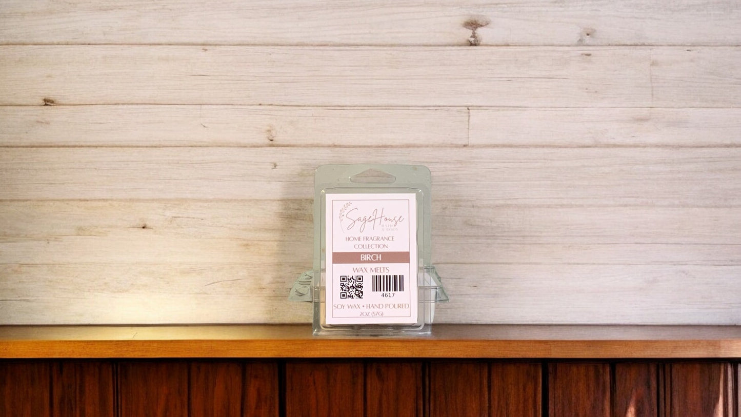 A clear clamshell container holding 6 wax melt cubes with a label on top, placed on a wooden surface against a wooden background.