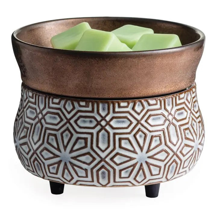 A bronze geometric-patterned fragrance warmer with a dish containing green wax cubes on top.