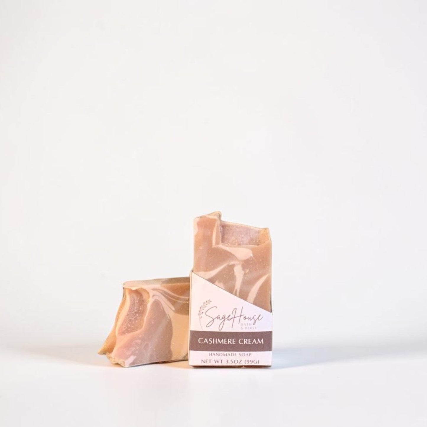Two wrapped artisan soap bars standing upright on a white surface against a white background.