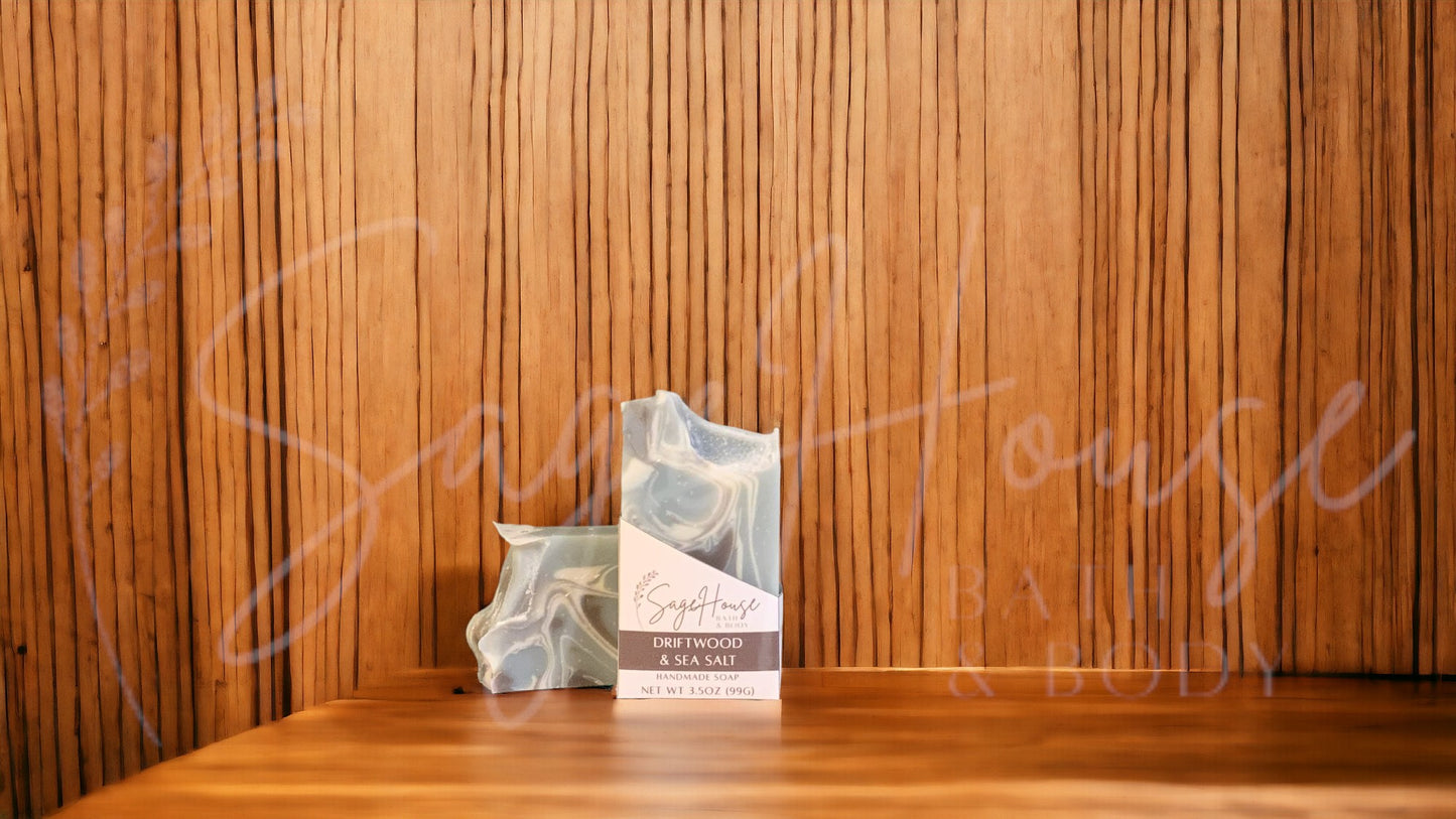 A light blue colored bar of soap with accents of brown and white, in a white labeled box, on a wood surface.