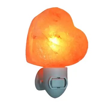 A pink Himalayan salt lamp in the shape of a heart , mounted on a plug in switch.