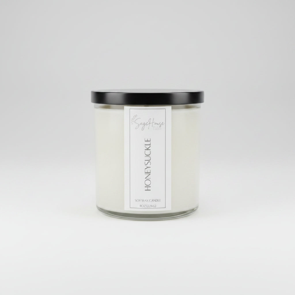 A white soy wax candle in a clear container, placed on a neutral background.