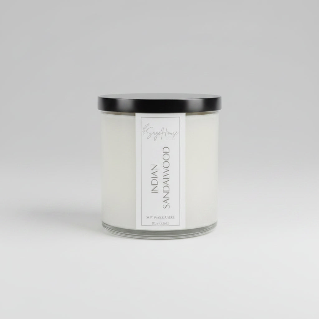 A white soy wax candle in a clear container, placed on a neutral background.