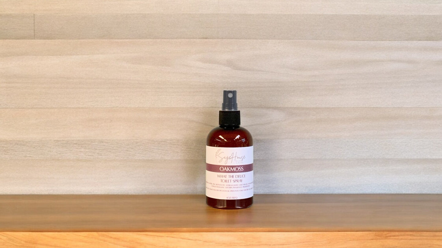 Amber colored spritz bottle with oakmoss label, on wood surface