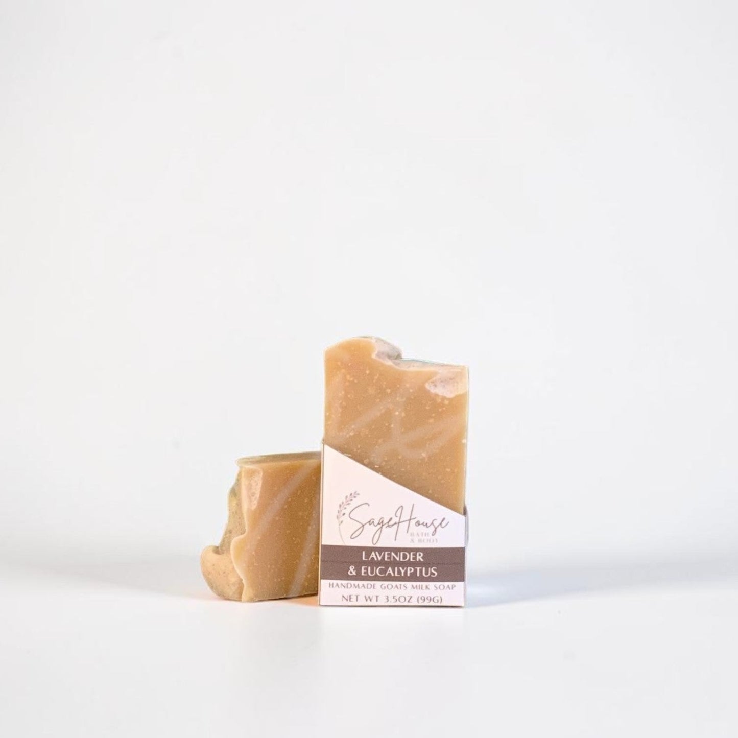 A labeled bar of soap sitting in front of a matching bar of soap. On a white background.