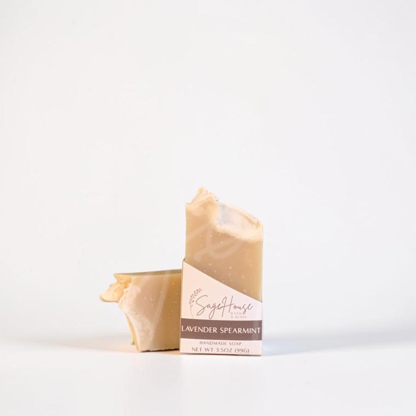A labeled bar of soap sitting in front of a matching bar of soap. On a white background.
