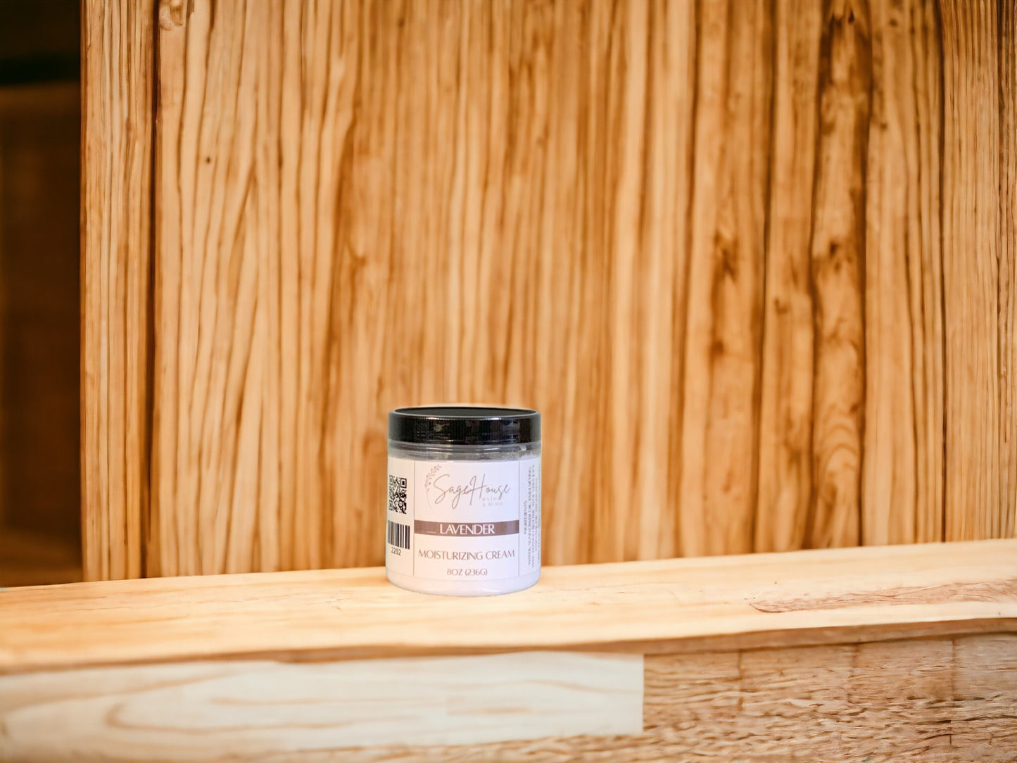 A jar of Lavender Moisturizing Cream standing in front of a wooden background.