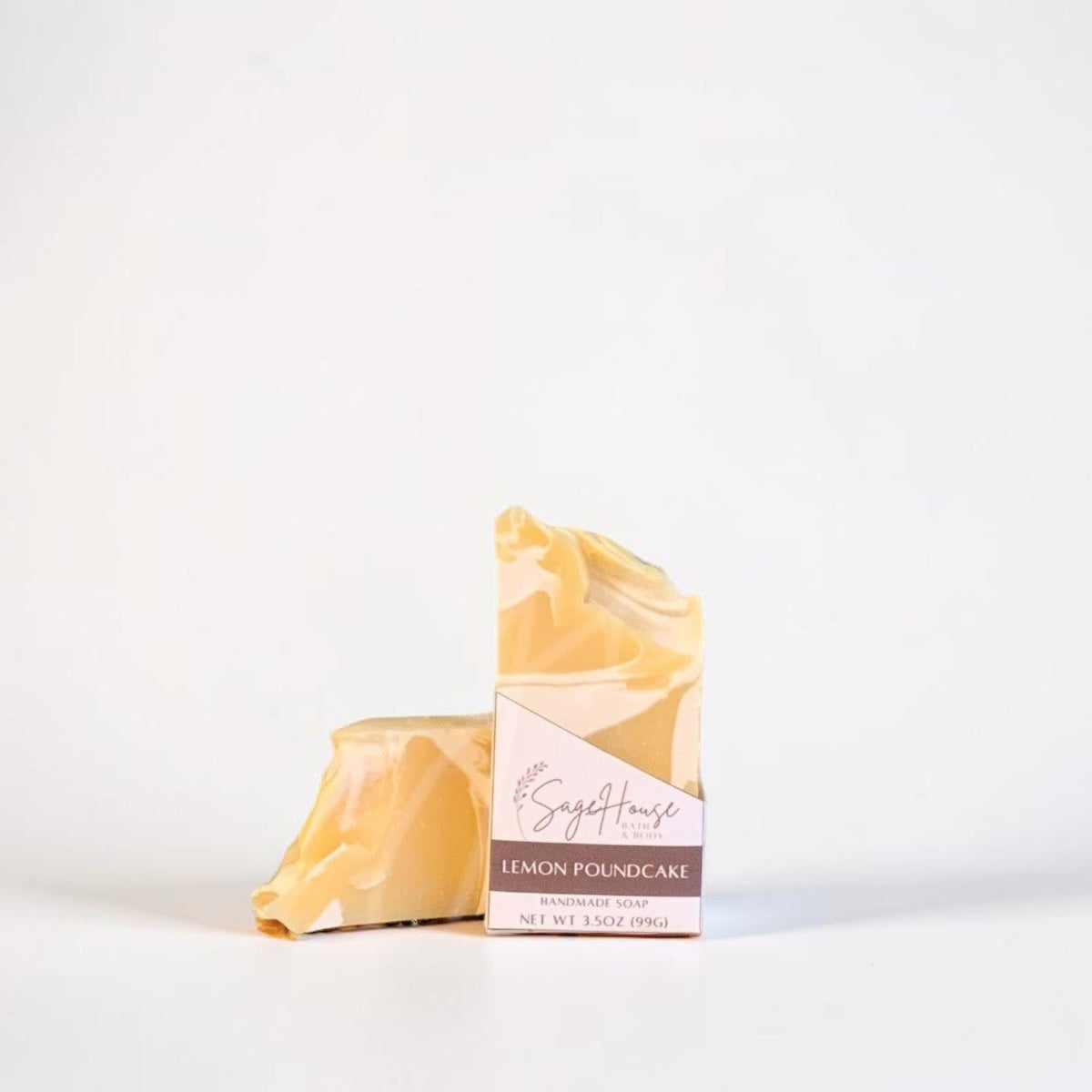 A small bar of soap in a labeled sleeve. Sitting in front of a matching bar of soap. On a white background.