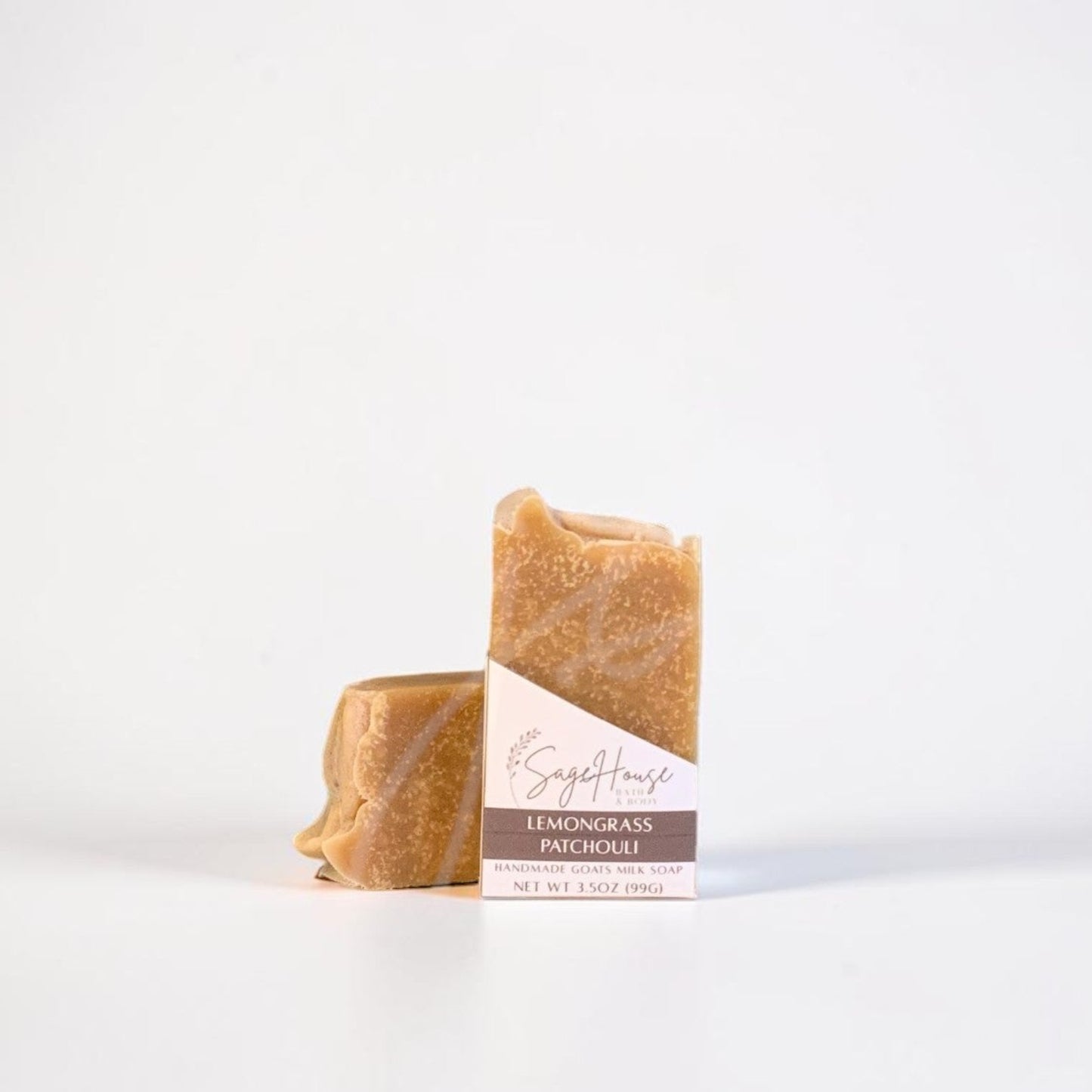 A labeled bar of soap sitting in front of a matching bar of soap. On a white background.