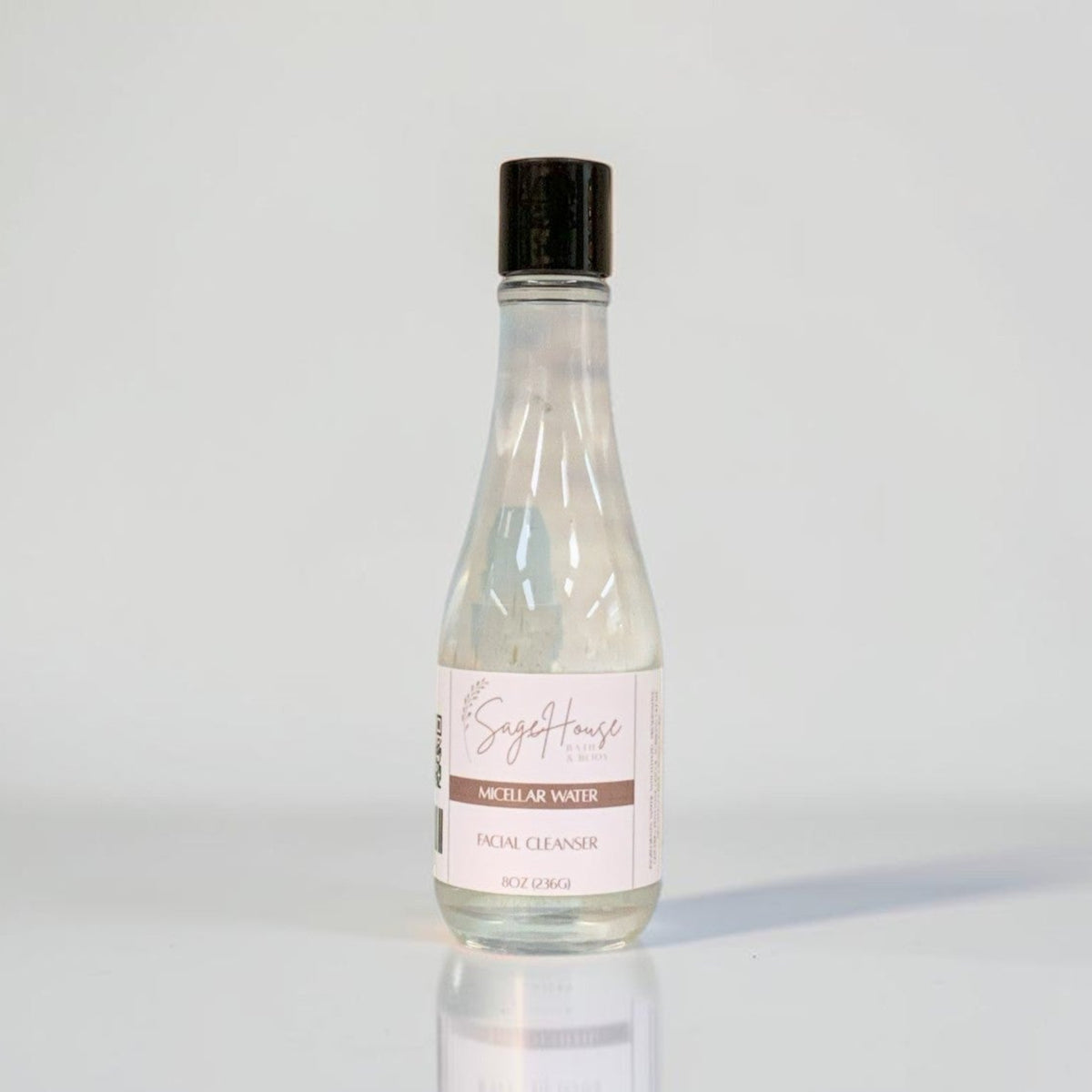 A clear bottle with a black cap and white label. On a light gray background.
