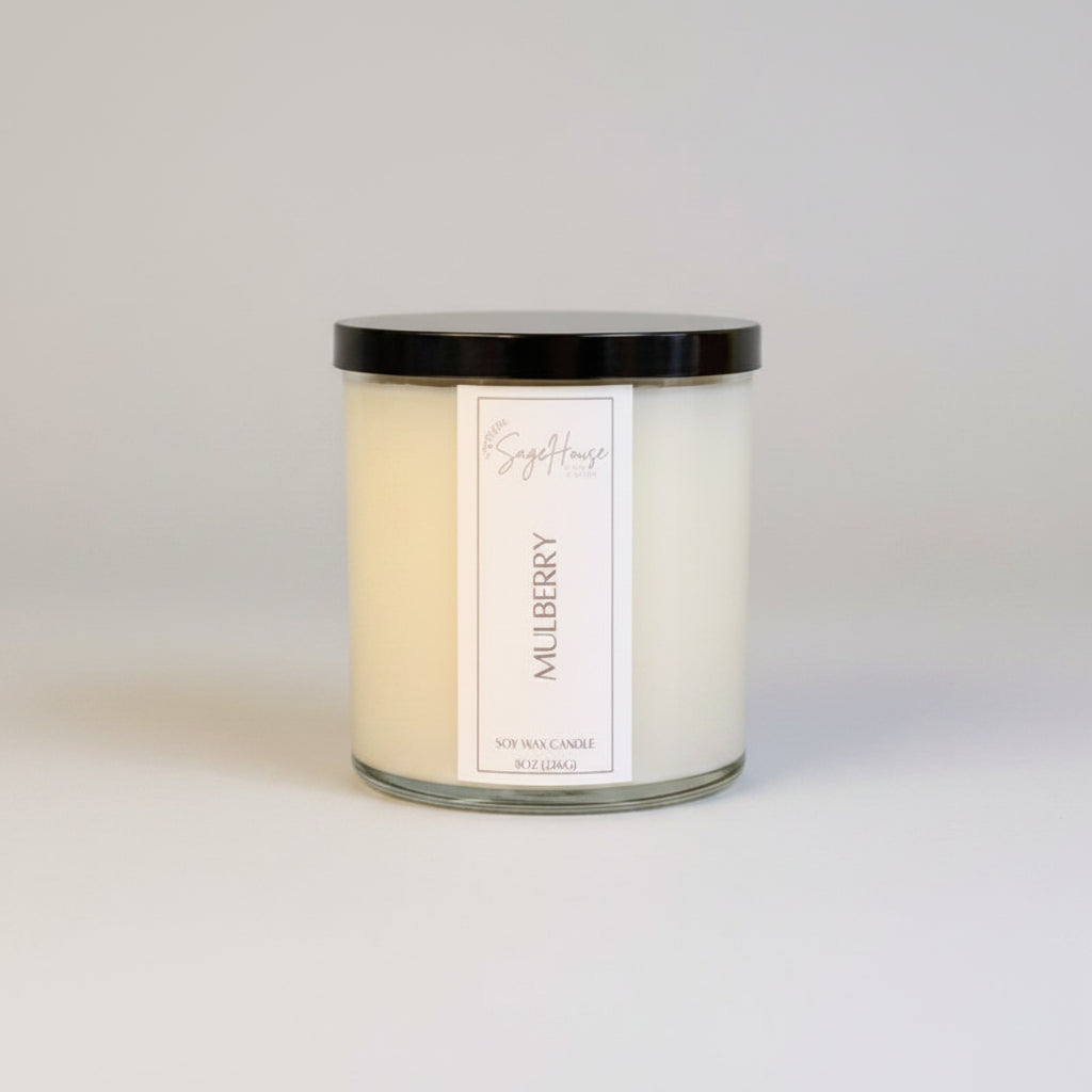 A white soy wax candle in a clear container, placed on a neutral background