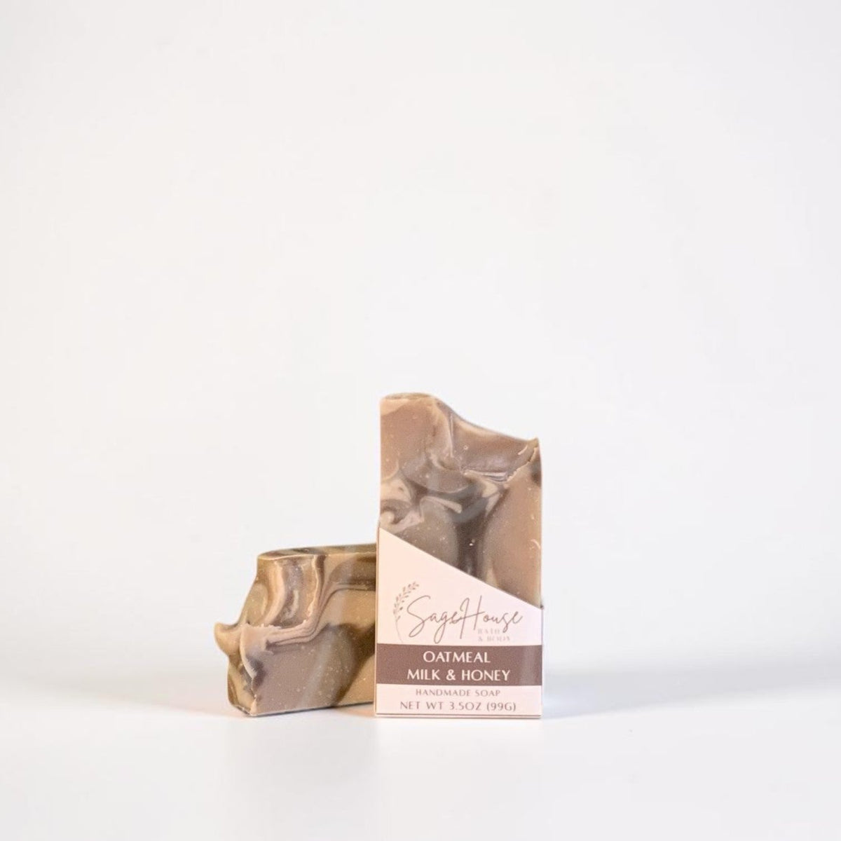 A bar of soap in its labeled sleeve standing upright beside it on a clean white studio background.