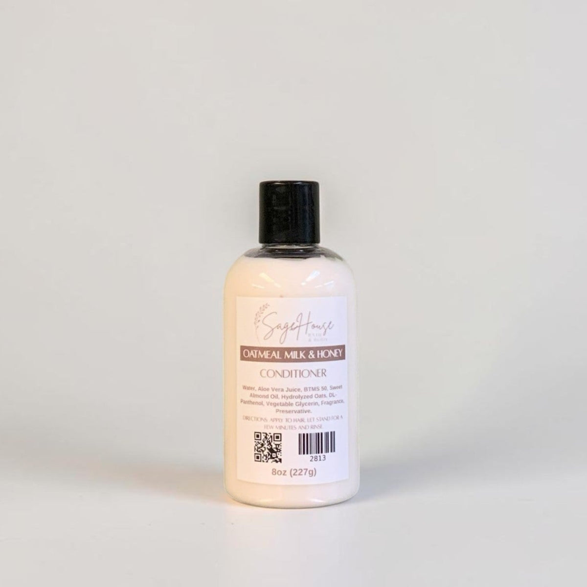A bottle of conditioner with a black lid and white label. On a white background.