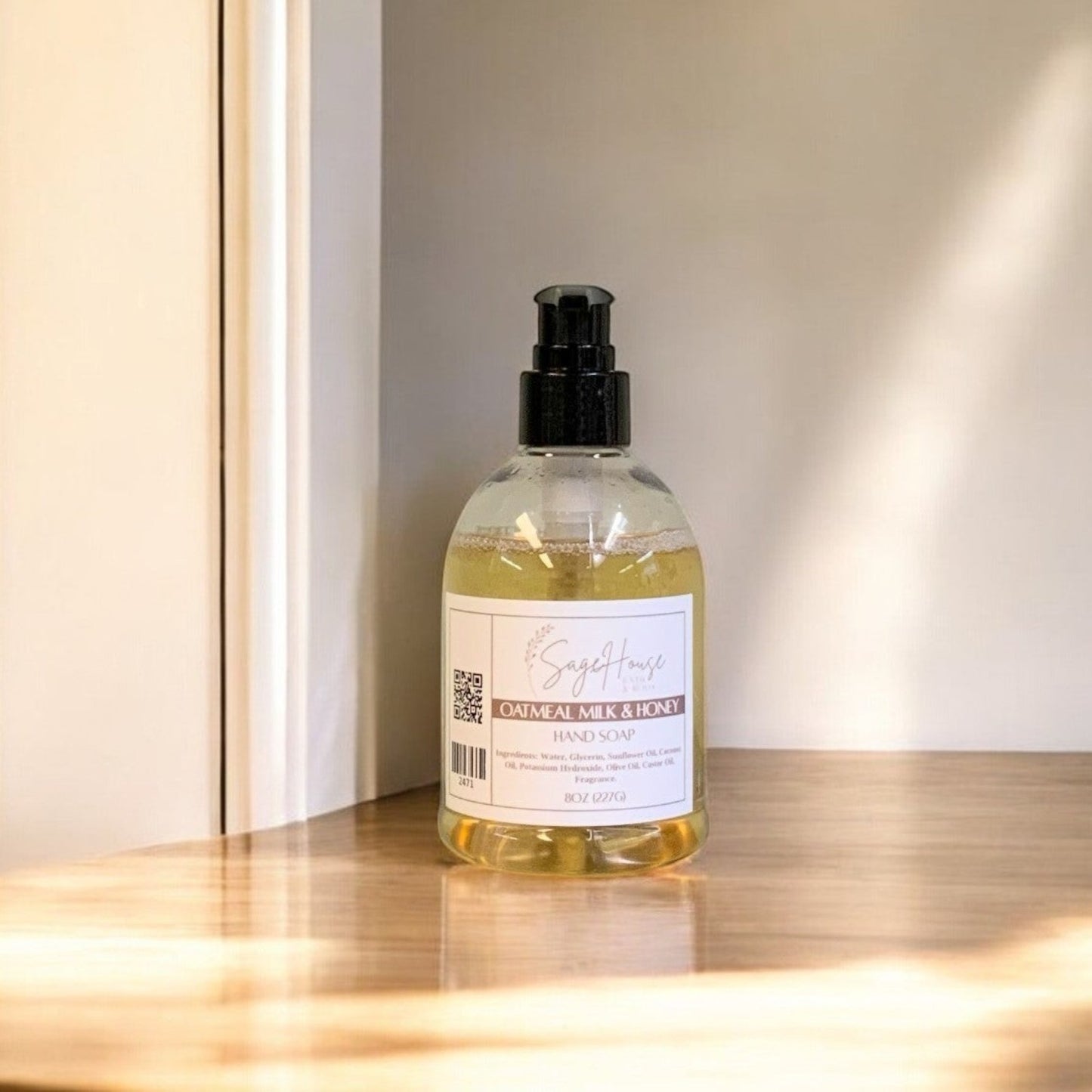 A clear plastic bottle of hand soap with a black cap, placed on a wooden surface with natural lighting.