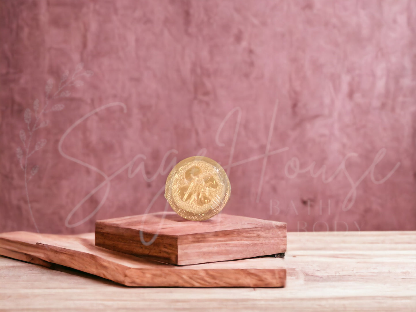 A tan colored bar of oatmeal milk and honey loofah soap resting on a wooden soap dish, with a pink background.