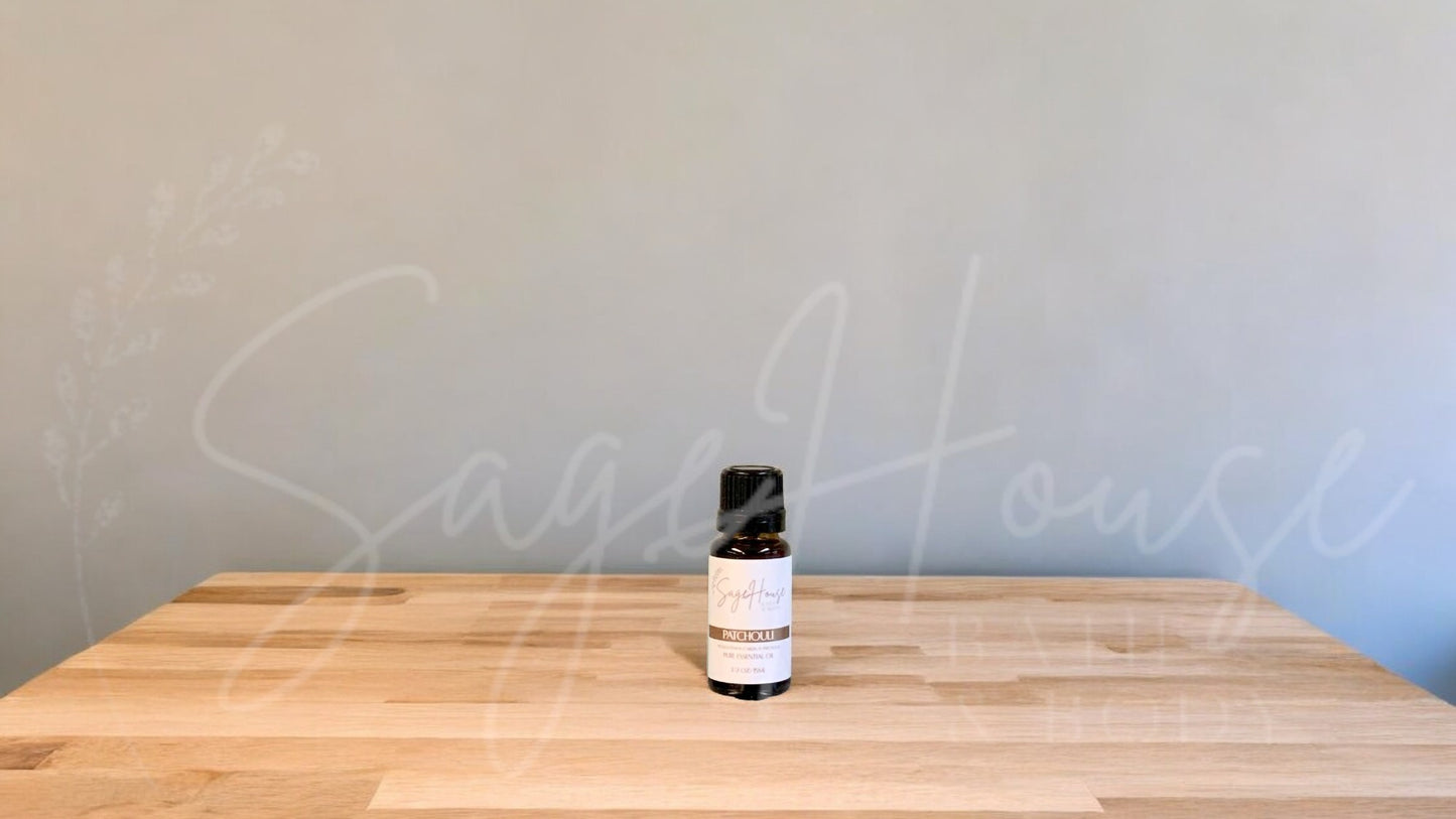 A small bottle of Patchouli essential oil is placed on a wooden surface with a plain background.