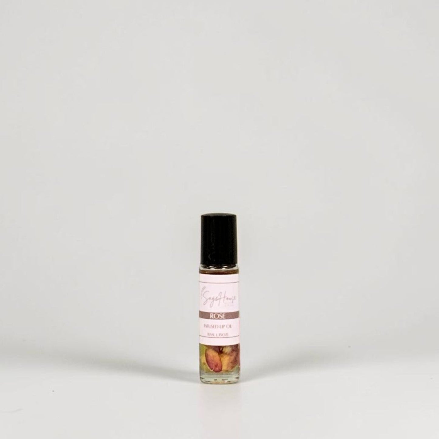 A small glass roller bottle with a black cap and a white label, standing on a light gray background.