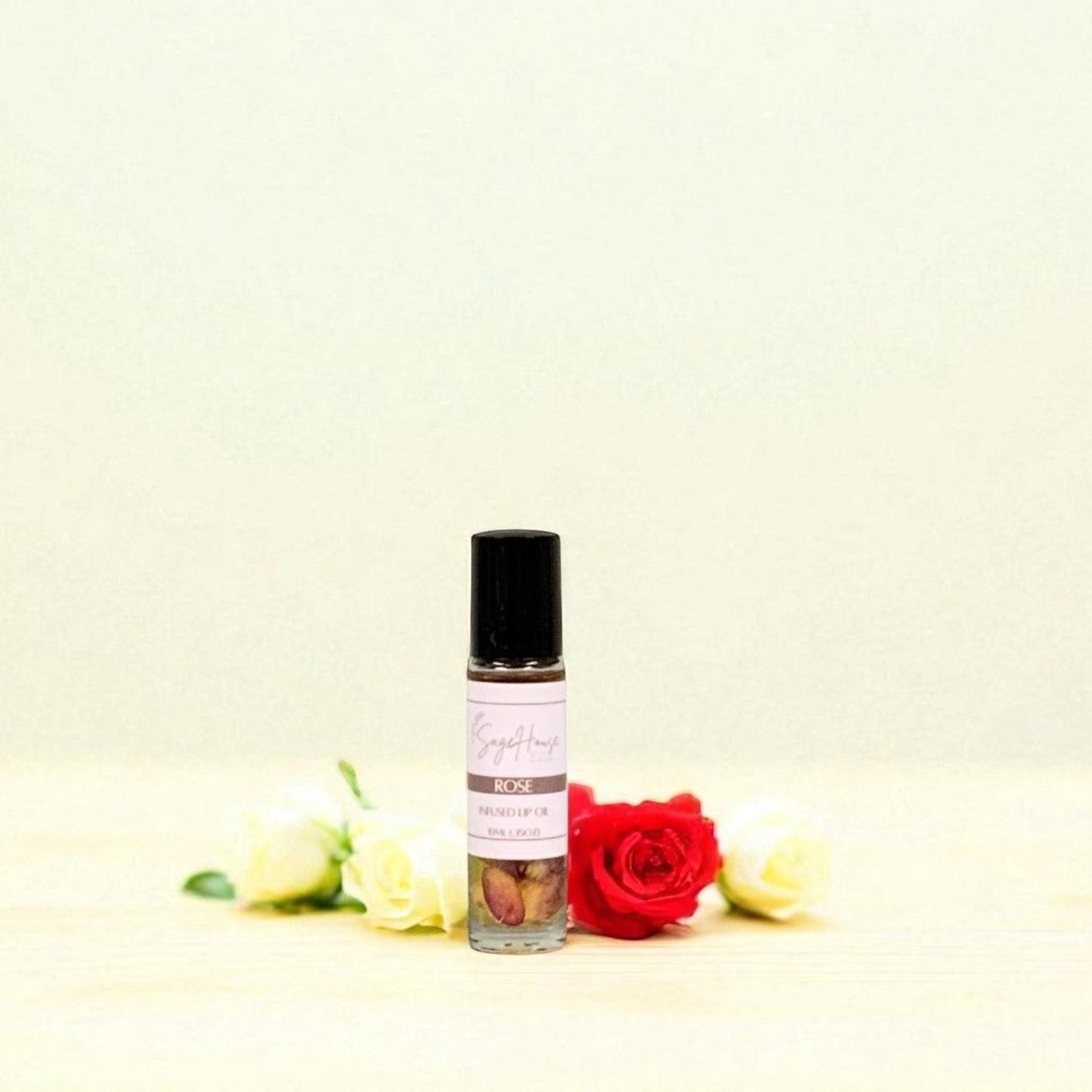 Small bottle of lip oil with rose petals surrounding, on a light background