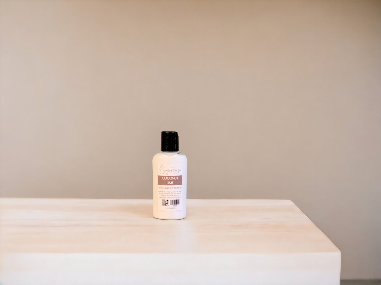 A small bottle of lotion, sitting on a light wood surface, with a tan background.