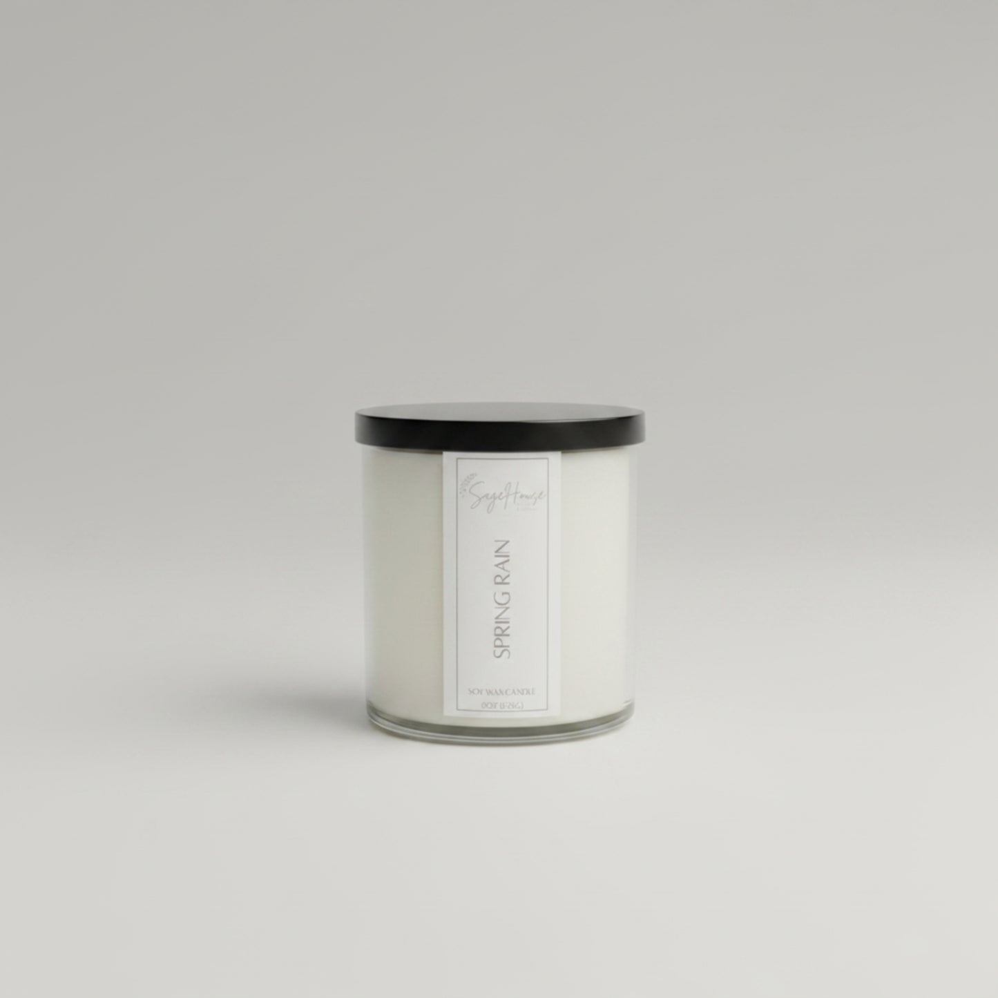 A white soy wax candle in a clear container, placed on a wooden surface, with a label on the front.