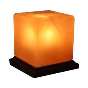 A square shaped salt lamp illuminated and fixed on a dark wood base