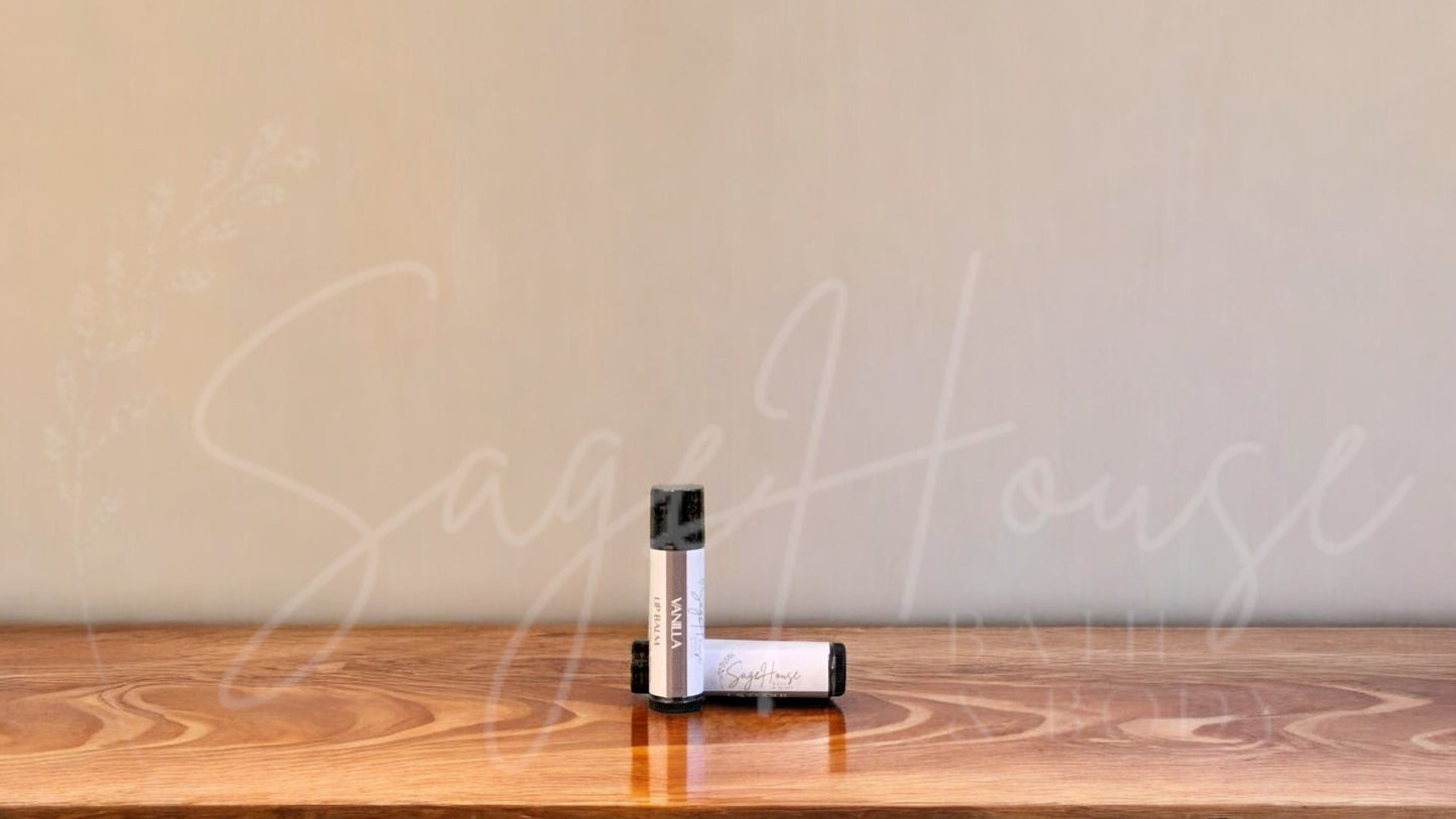 A tube of vanilla lip balm placed upright with a tube lying behind it, on a wooden surface.