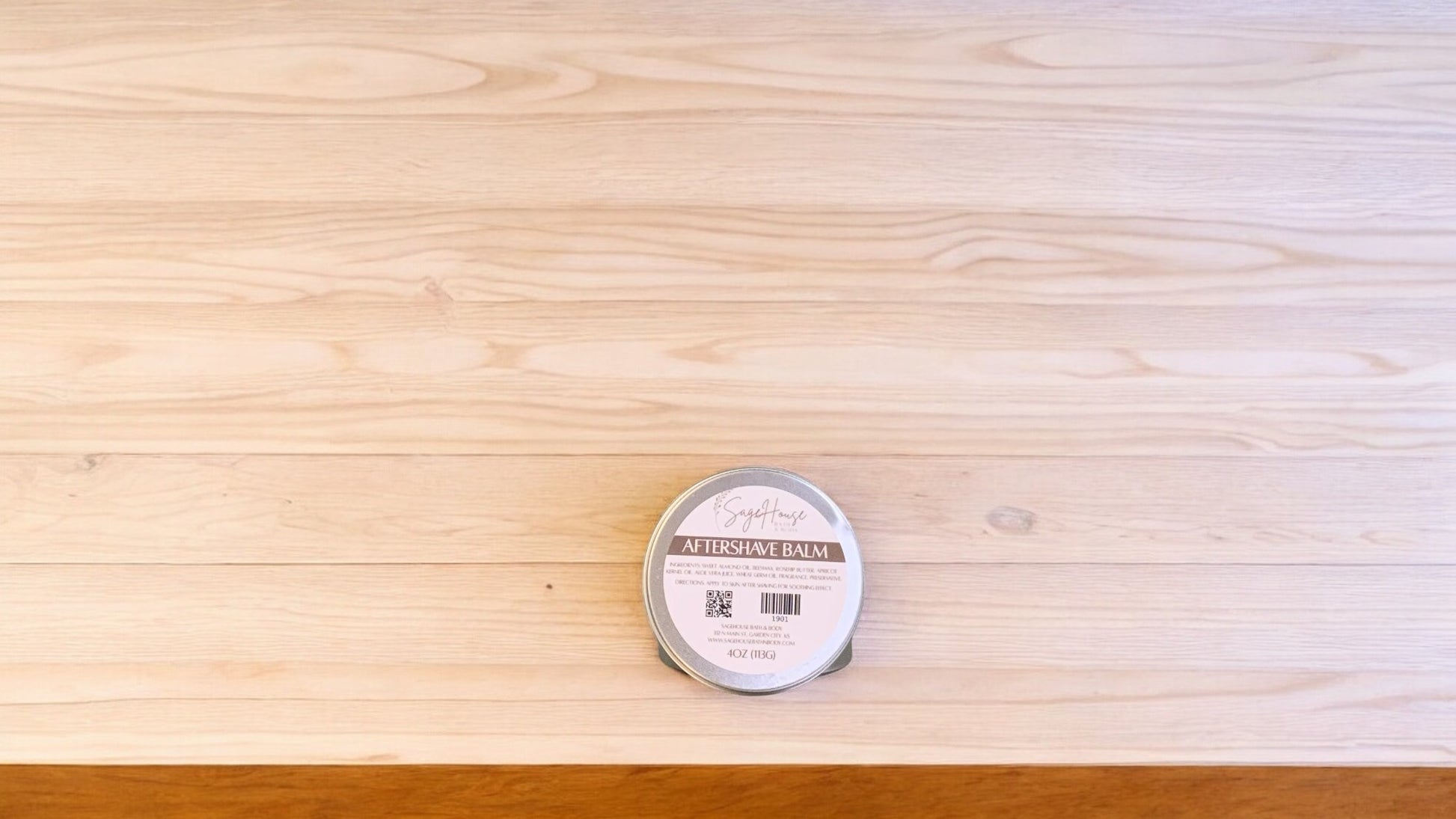 A small aftershave balm container, placed on a wooden surface.