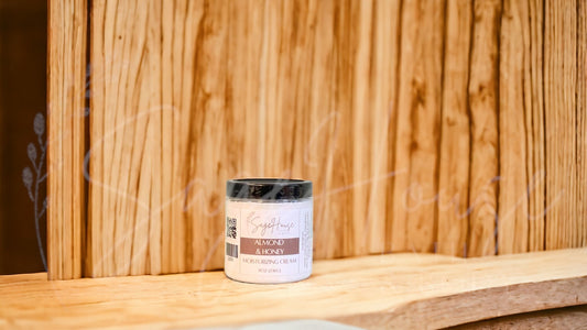 A jar of Almond & Honey Moisturizing Cream against a wooden backdrop.