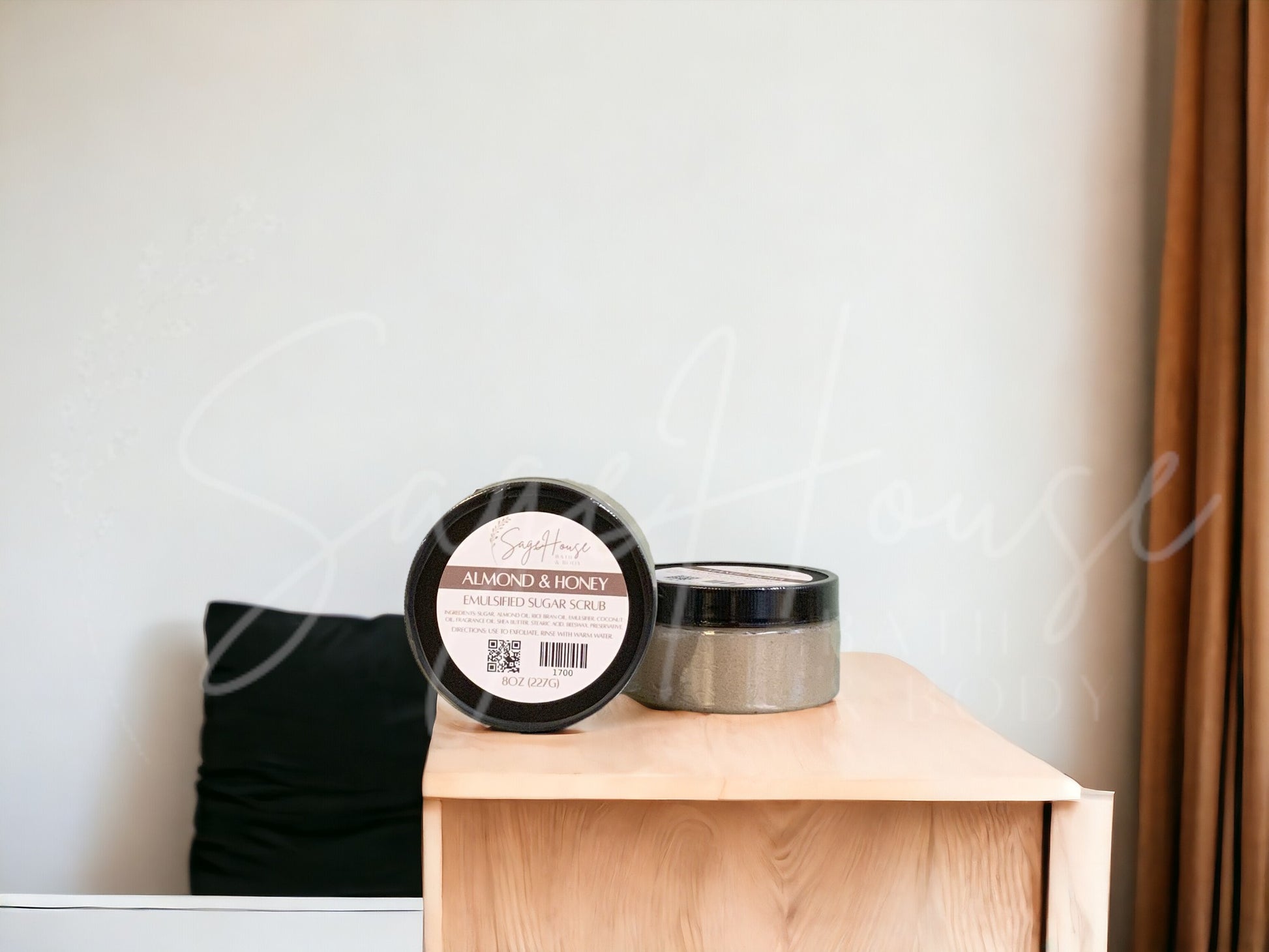 A jar of Almond And Honey Sugar Scrub is placed on a wooden surface.