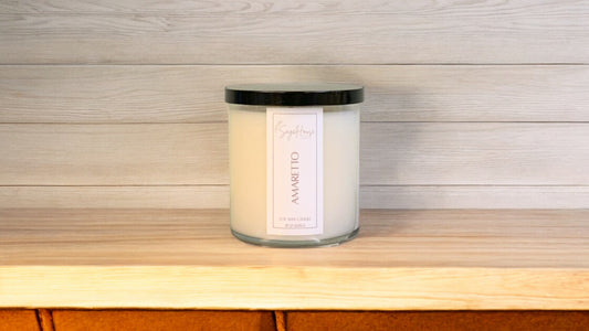 A white soy wax candle in a clear container, placed on a wooden surface, with a label on the front.