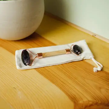 A amethyst roller with gold hardware and a roller on each end