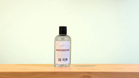 Bottle of "apple honey champagne" body wash on a wooden surface with a light background