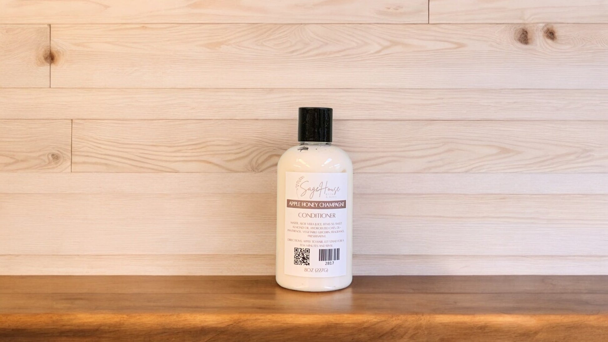 A bottle of conditioner with a black cap. Sitting on a wood surface with a light wood background