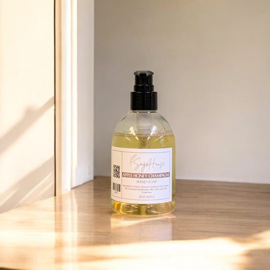 A clear plastic bottle of hand soap with a black cap, placed on a wooden surface with natural lighting.