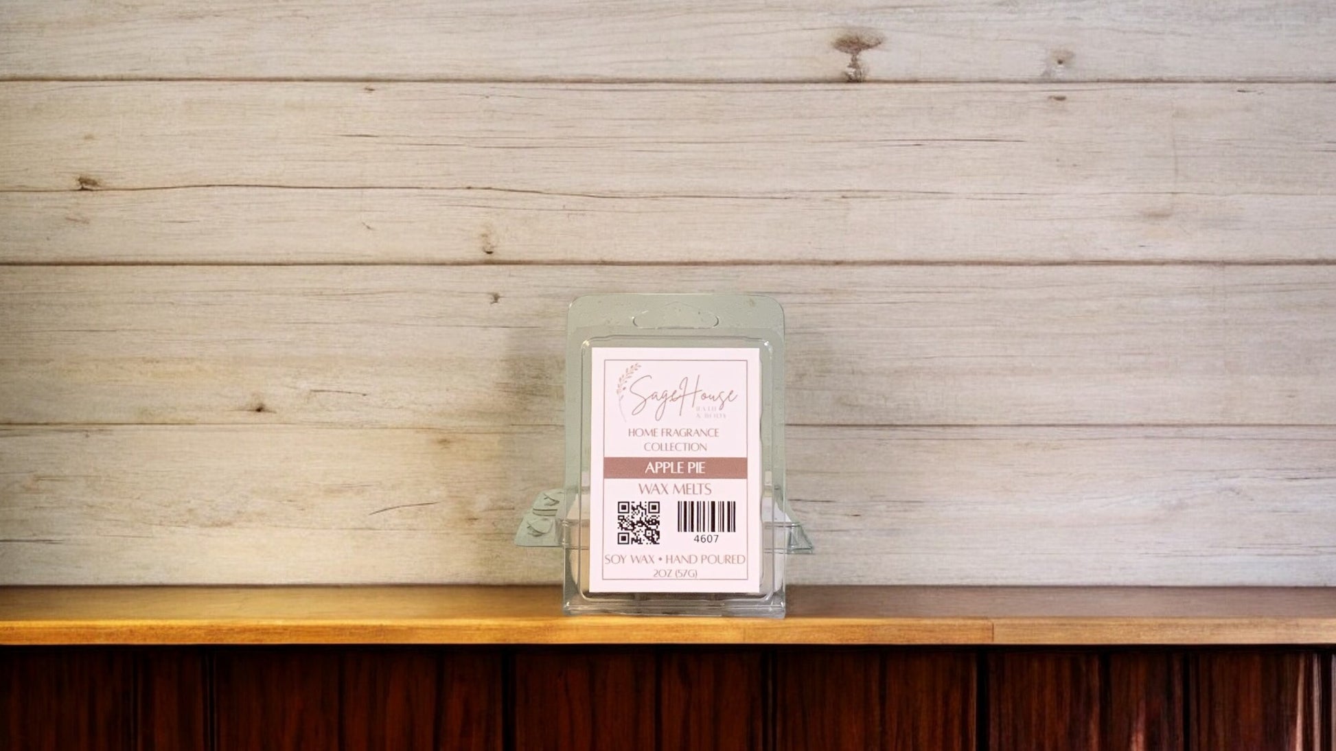 A clear clamshell container holding 6 wax melt cubes with a label on top, placed on a wooden surface against a wooden background.
