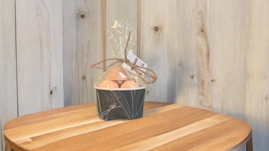 A set of bath truffles, wrapped in clear packaging with a decorative ribbon. placed on a wooden surface.