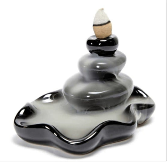 A black glass incense burner designed for backflow cones, with a small amount of incense placed on top.