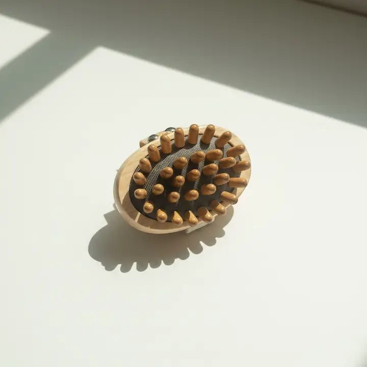 A massage brush with nubs with a shadow on a white background