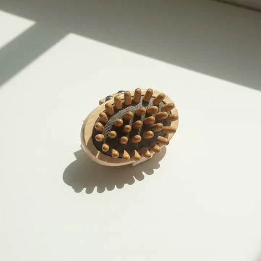 A massage brush with nubs with a shadow on a white background