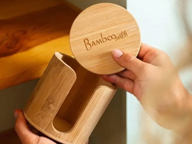 A person is holding a bamboo holder with the brand name 'Bamboo' inscribed on it, demonstrating its use for storing a reusable facial round.