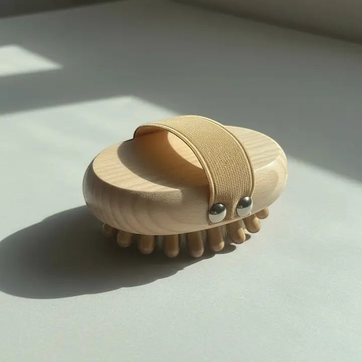 A massage brush with nubs and handle. On a white surface with its shadow in the background