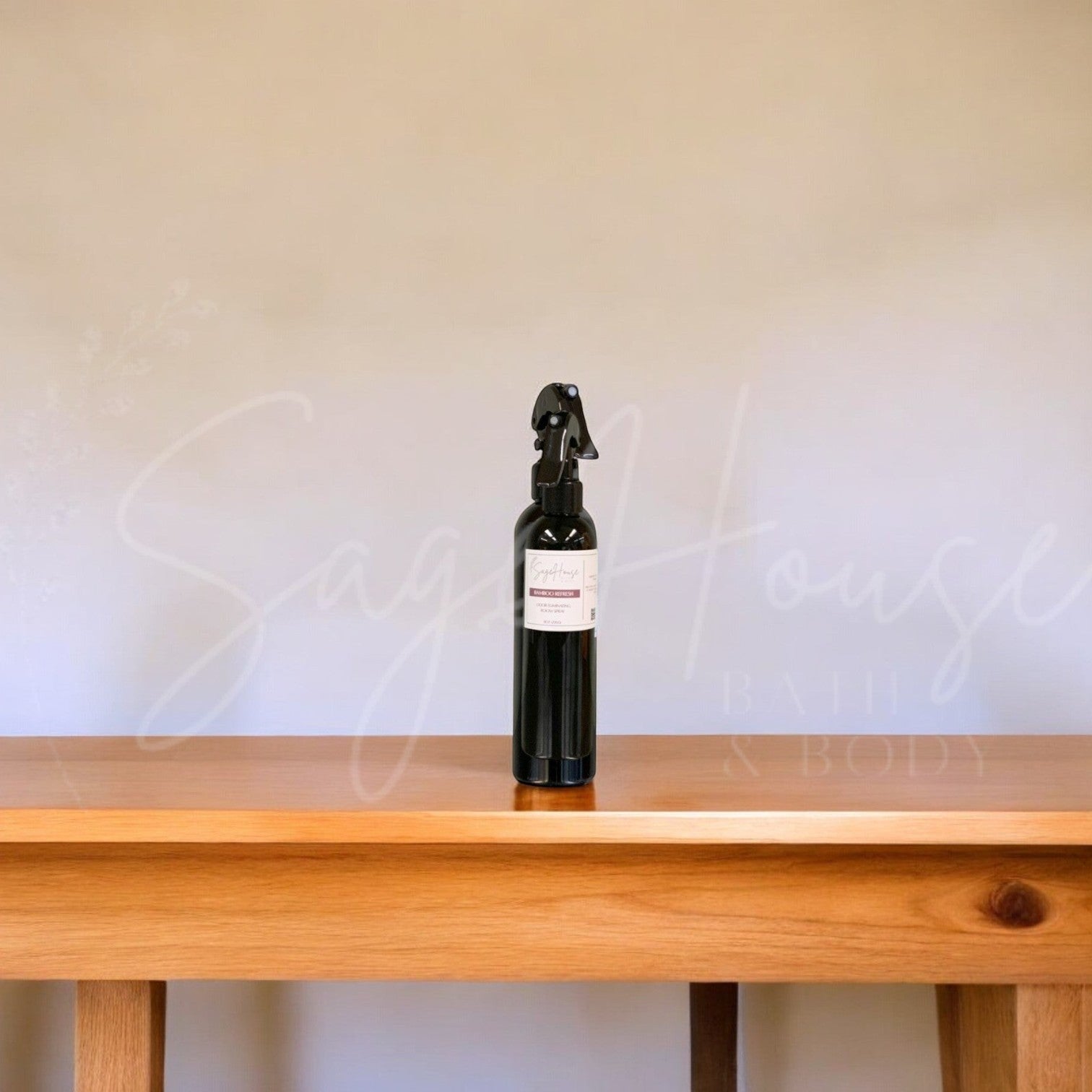 A black bottle with black nozzle sprayer placed on a wood table, with a white background