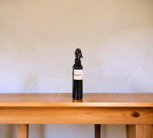 A black bottle with black nozzle sprayer placed on a wood table, with a white background